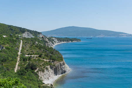 Landscape of the blue sea with a green high coast against the blue sky on a sunny dayの写真素材