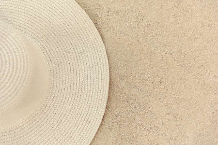 Yellow straw women's hat lies on the sand, top view, half of the hatの写真素材