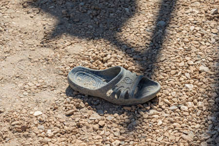 Lost rubber slipper lies on the gravelの写真素材