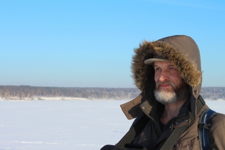 The man with a beard in winter clothes on a snow field against the blue skyの写真素材