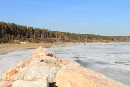 Stones on the river in the spring among snowの写真素材