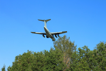The plane flies on landing against the sky and treesの写真素材