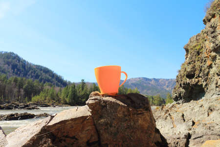 The yellow mug is on a stone on the bank of the mountain riverの写真素材