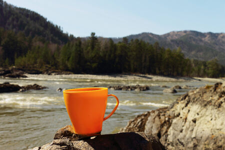The yellow mug is on a stone on the bank of the mountain riverの写真素材