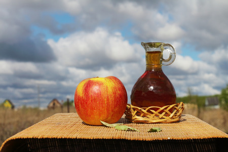 Apple and jug with juice are on a table outdoorsの写真素材