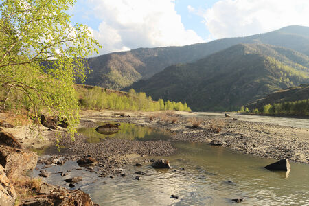 The river flows among mountains and rocky coast against the skyの写真素材