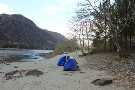 Tents stand on stones at the river against the skyの写真素材