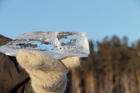 Ice crystal in the female hands dressed in woolen mittens in the winter