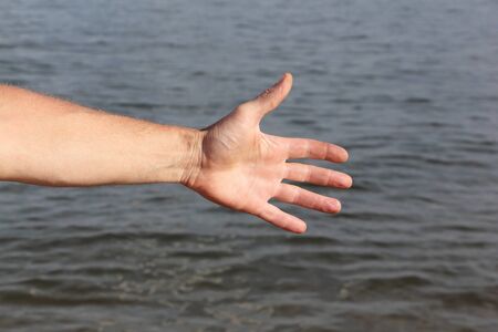 Suntanned male hand against a surface of the waterの写真素材