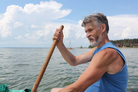 The man with a beard rowing with an oar on the riverの写真素材