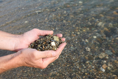 Male palms with damp river sand against a surface of the water