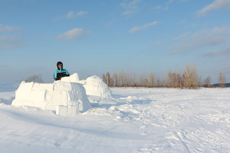 Man building an igloo of snow blocks  on a glade in the winter