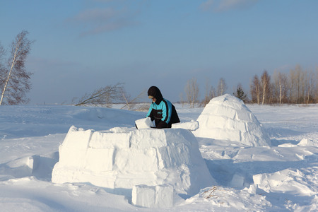 Man building an igloo of snow blocks  on a glade in the winterの写真素材