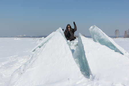 Man in sunglasses climbing a cracked ice on a river, Ob River, Russia