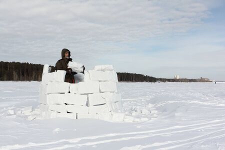Man building an igloo from snow blocks in the winter, Novosibirsk, Russiaの写真素材