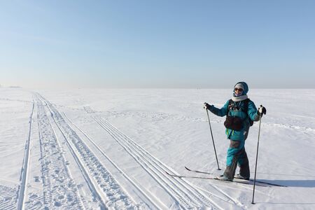 Happy woman with a photo bag, backpack and video camera, skiing on the snow surface on a frozen river, Ob reservoir, Novosibirsk, Russiaの写真素材