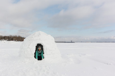 Woman in a green jacket sitting in an igloo in winter, Novosibirsk, Russia 