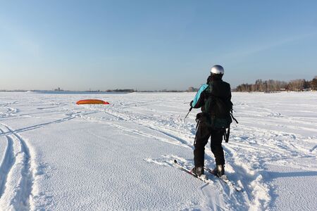 Man man lifting a kite from the snowy surface of a reservoir, Novosibirsk, Russiaの写真素材