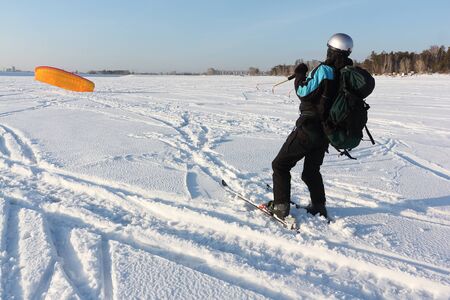 Man man lifting a kite from the snowy surface of a reservoir, Novosibirsk, Russia の写真素材