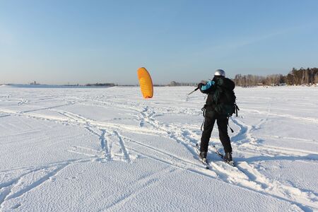 Man man lifting a kite from the snowy surface of a reservoir, Novosibirsk, Russia の写真素材