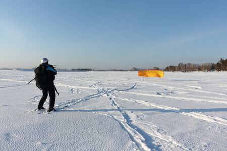 Man man lifting a kite from the snowy surface of a reservoir, Novosibirsk, Russia の写真素材