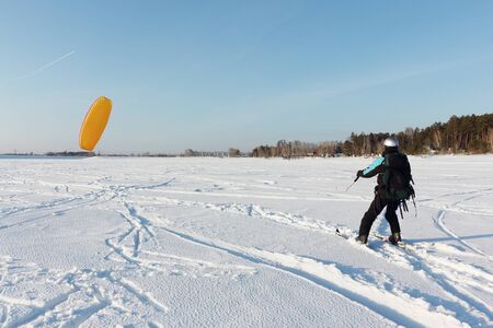 Man man lifting a kite from the snowy surface of a reservoir, Novosibirsk, Russia の写真素材