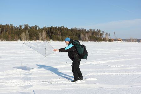 Man with a backpack launches a kite in the winter on snow, Novosibirsk, Russiaの写真素材