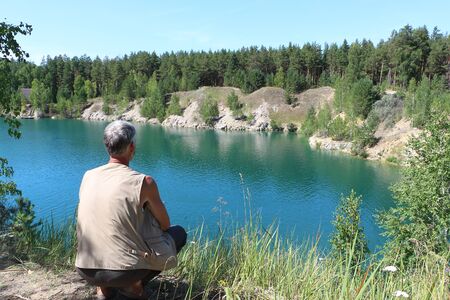 Man sitting on the shore of a lake, Marmara Lake, Novosibirsk region, Russiaの写真素材