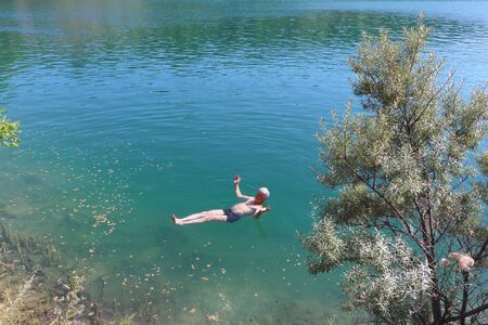 Man lying motionless on his back on the water surface of a freshwater lake, Marmara Lake, Novosibirsk Region, Russiaの写真素材