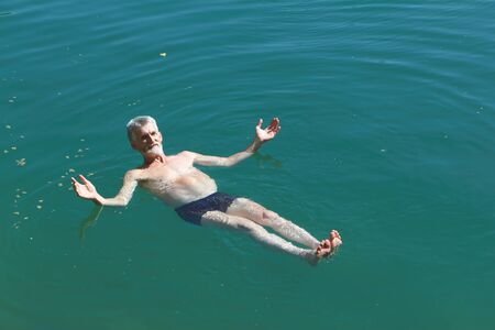 Man lying motionless on his back on the water surface of a freshwater lake, Marmara Lake, Novosibirsk Region, Russiaの写真素材