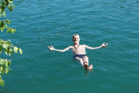 Man lying motionless on his back on the water surface of a freshwater lake, Marmara Lake, Novosibirsk Region, Russiaの写真素材