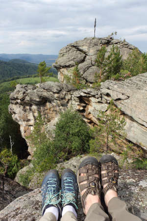 Male and female legs in trekking shoes on the top of the mountain, rocks Ambarchiky, Altai Mountains, Belokurikha City, Russiaの写真素材