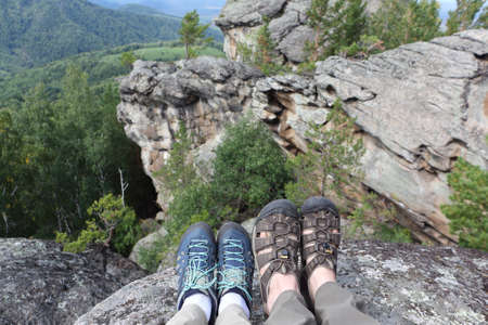 Male and female legs in trekking shoes on the top of the mountain, rocks Ambarchiky, Altai Mountains, Belokurikha City, Russiaの写真素材