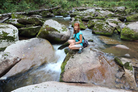 Happy woman with red hair standing on a stone by the river in summer, Belokurikha River, Belokurikha City, Altai Mountains, Russiaの写真素材