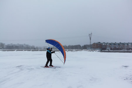Man doing snowkiting in a blizzard on a frozen river in winter, Ob reservoir, Novosibirsk, Russiaの写真素材