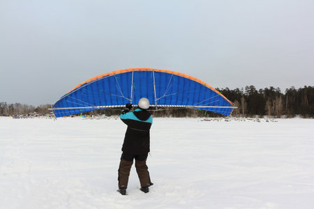 Man training with a kite on a frozen river in winter, Ob reservoir, Novosibirsk, Russiaの写真素材