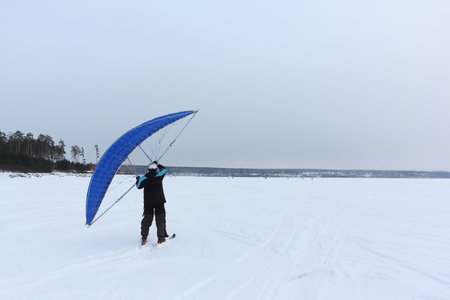 Man training with a kite on a frozen river in winter, Ob reservoir, Novosibirsk, Russiaの写真素材
