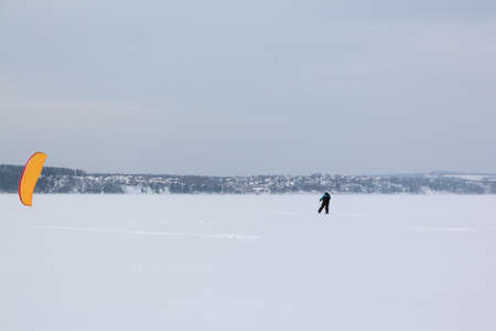 Man training with a kite on a frozen river in the winter, Kama Reservoir, Perm city, Russiaの写真素材