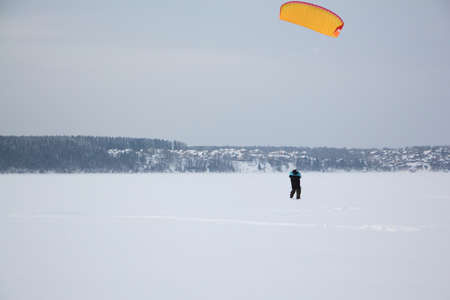 Man training with a kite on a frozen river in the winter, Kama Reservoir, Perm city, Russiaの写真素材
