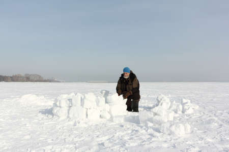 Man building an igloo from snow blocks in the winter, Ob reservoir, Novosibirsk, Russiaの写真素材