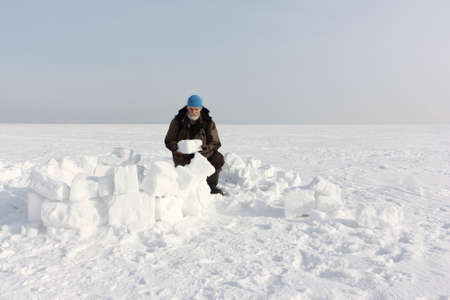 Man building an igloo from snow blocks in the winter, Ob reservoir, Novosibirsk, Russiaの写真素材
