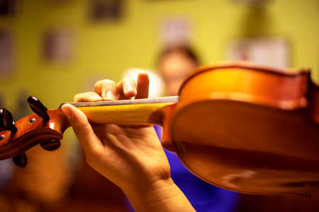 young violinist plays music on the violin with his back near the piano, horizontalの写真素材