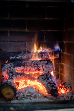 flames of fire in a burning wood stacked in a stone fireplace vertical format