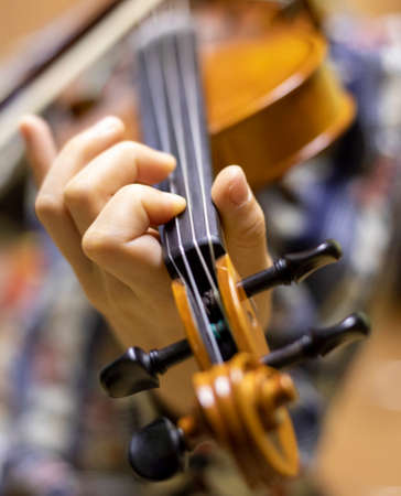 blurry left hand of a young violinist presses the strings on the violin neck, horizontalの写真素材