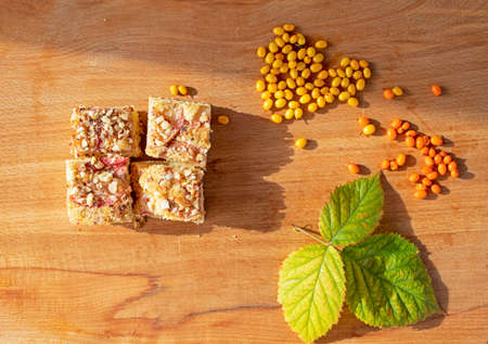 Good Morning Pieces of Pie with Sea Buckthorn and Blackberry Leaves on a Wooden Surface, Flat Lay, Horizontalの写真素材