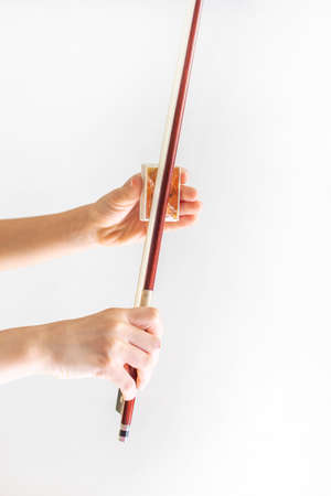 hands of a young violinist rosin his bow on the background of a piano illuminated by the sun, verticalの写真素材