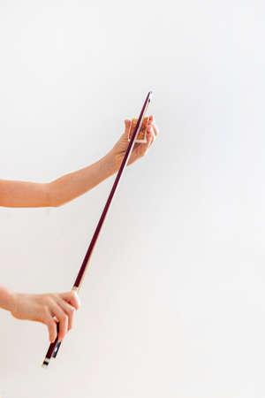 hands of a young violinist rosin his bow on a light background, verticalの写真素材