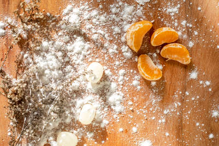 festive christmas background with plants, tangerine lollipops and powdered sugar on a wooden surface top view,の写真素材