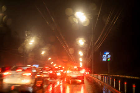 abstract blurred background on the windshield of a car with bright lights during a traffic jam in the rainの写真素材