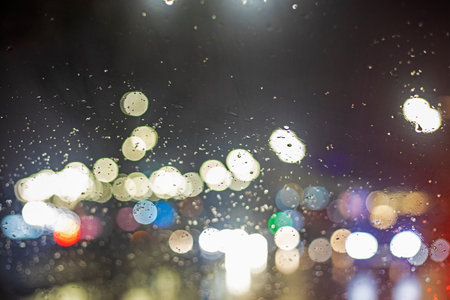 abstract blurred background on the windshield of a car with bright lights during a traffic jam in...